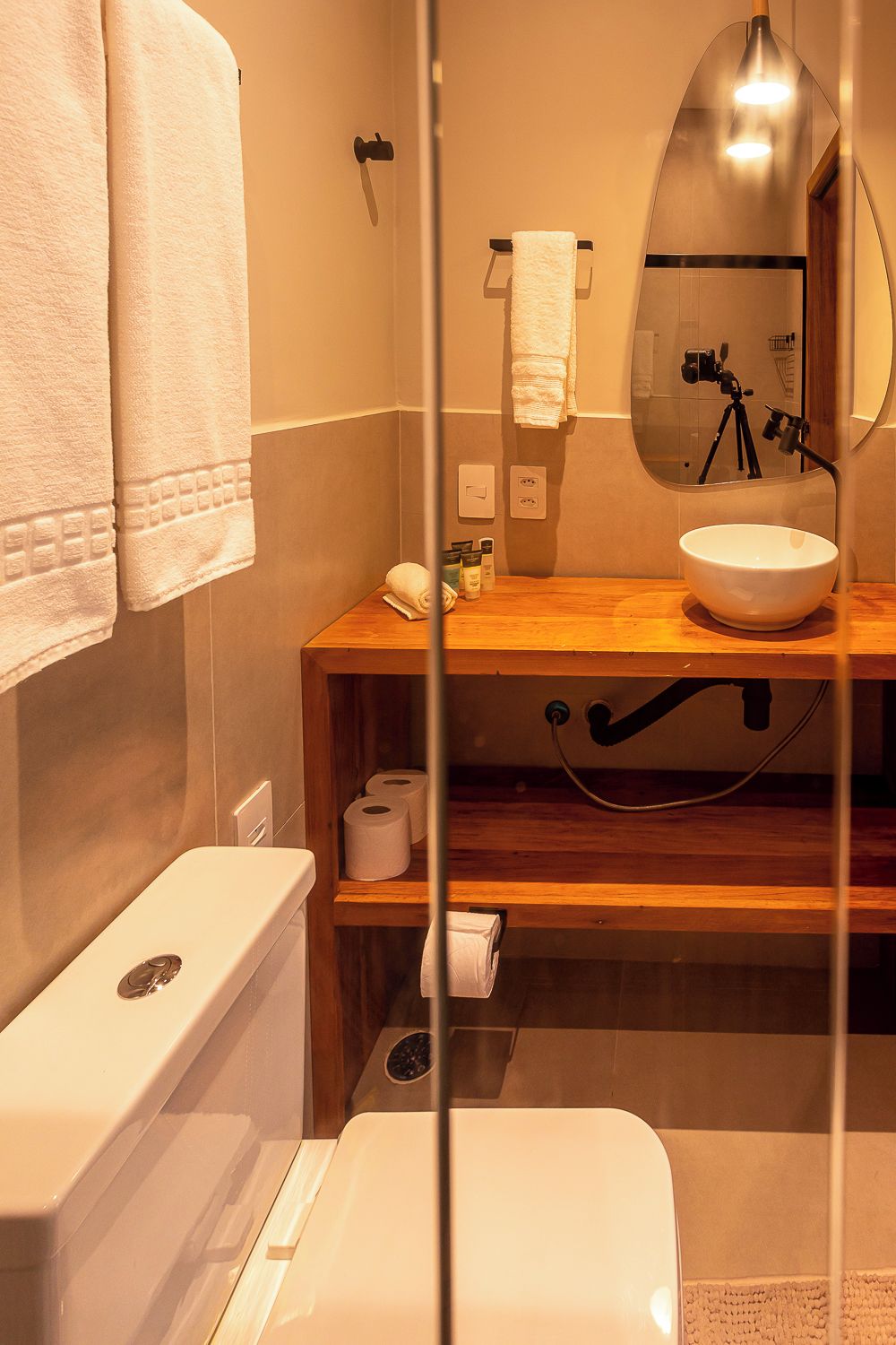 A compact bathroom with a wooden vanity, a white sink, a mirror, and a toilet.