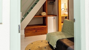 Un espacio habitable compacto con una litera, una kitchenette pequeña y una escalera.