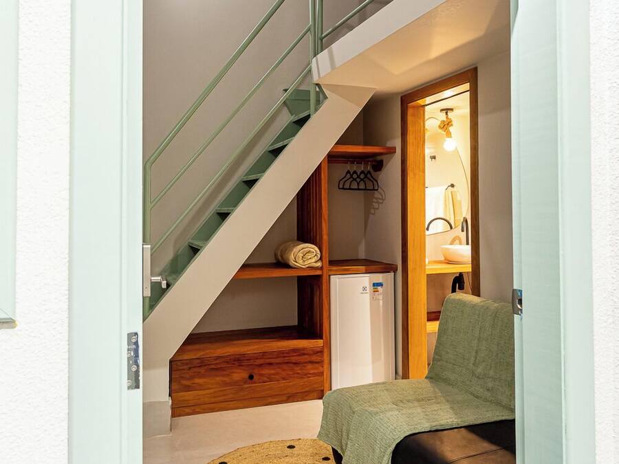 Un ambiente compatto con un letto a castello, un angolo cottura e una scala.