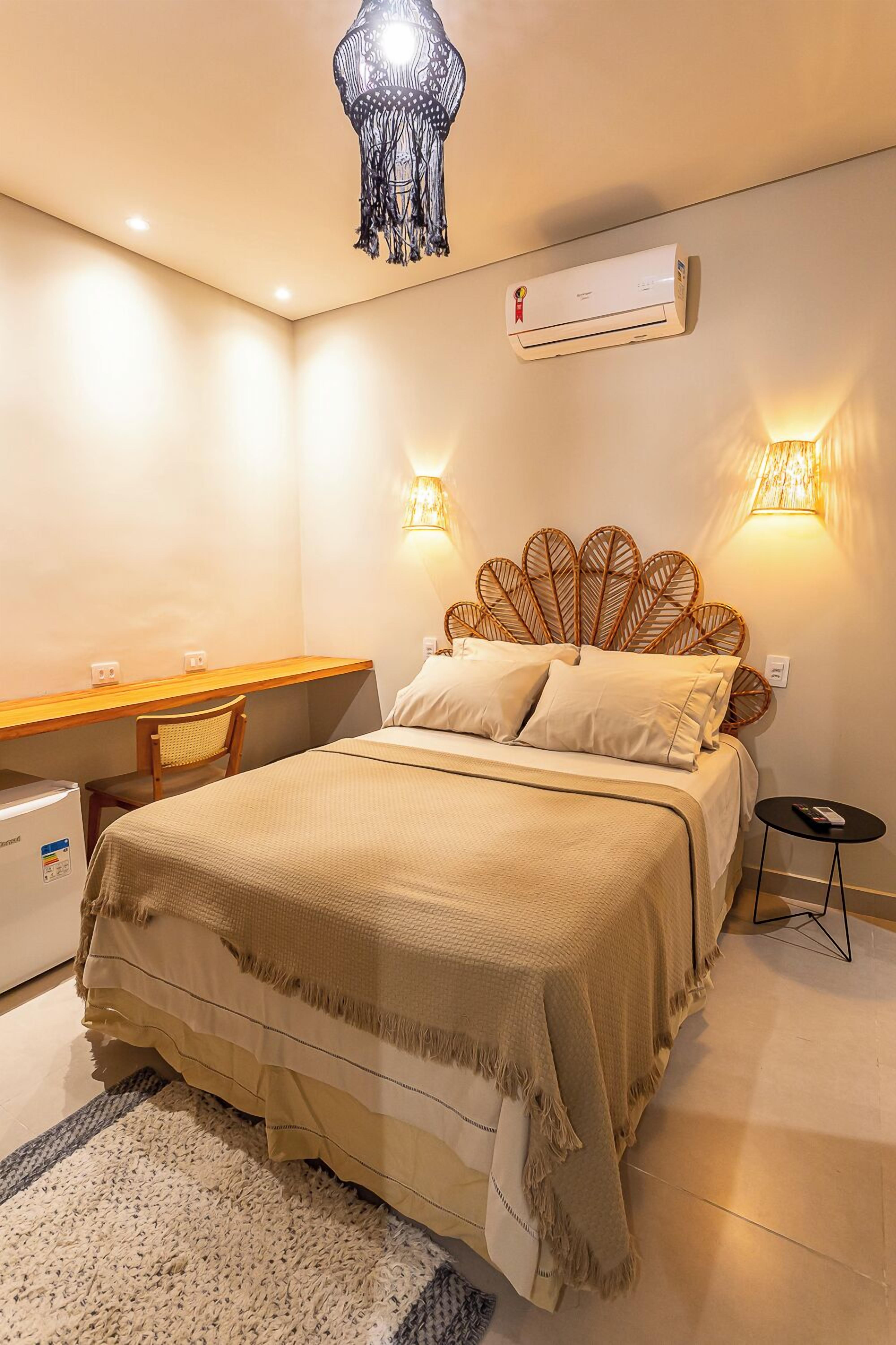 A bedroom with a bed, bedside lamps, a desk, and a chair.