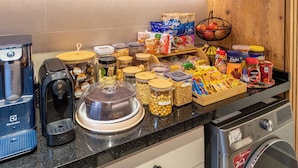 Una encimera de cocina con diversos alimentos, una cafetera y una lavadora.