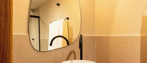 A bathroom with a wooden vanity, a white sink, and a mirror with a rope light fixture.