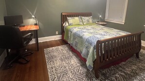 Ein Schlafzimmer mit Bett, Schreibtisch, Stuhl und Deckenventilator.