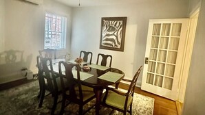 Ein Esszimmer mit Tisch, Stühlen, einem Deckenventilator, einem Fenster und einer Tür.