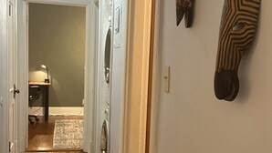 Ein Flur mit Holzboden, einer Waschmaschine und einer Tür zu einem anderen Raum.