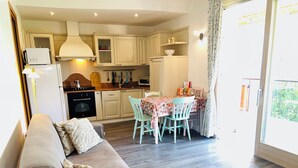 Una cocina moderna con armarios blancos, una mesa de comedor con sillas y un sofá en la sala de estar.