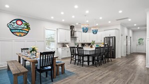 Una cocina moderna con armarios blancos, una isla central y luces colgantes.
