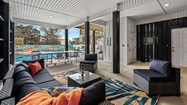 Un espace extérieur aménagé, abrité et doté d’une vue sur la piscine, comprenant une table à manger et un fauteuil de détente.