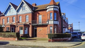 A Victorian-style building with a corner entrance, bay windows, and a red brick facade. - Treasure Cove-UK48780 (Whitby)