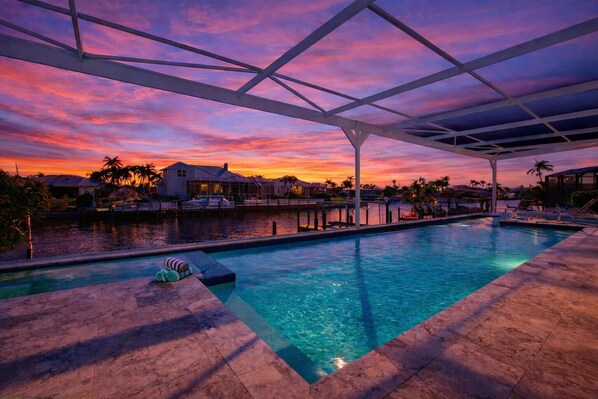 A swimming pool with a view of houses and a sunset.