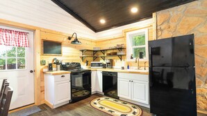 A compact kitchen with white cabinets, a black refrigerator, a microwave, a stove, and a dishwasher.