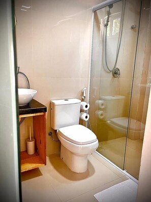 A modern bathroom with a toilet, sink, and glass shower enclosure. - Pousada Vila Flow (Caucaia)
