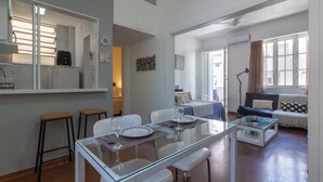 A modern living room with a glass dining table, white chairs, a sofa, and a coffee table. - Refuge in Copacabana for two | NSC1011 (Rio de Janeiro)