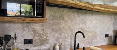 A kitchen with a microwave, stove, and wooden shelves.