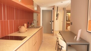 A modern kitchen with a wooden countertop, a built-in sink, and a dining area with a table and chairs. - Studio 2 pessoas 36m² - Wi-Fi Rapido e Estacao de Trabalho (Florianópolis)