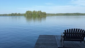 A wooden dock extending into calm water with a bench on the right.