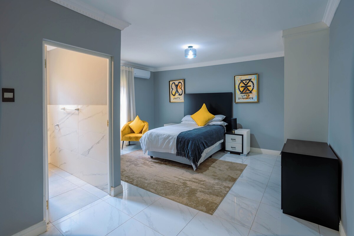 A bedroom with a bed, nightstands, a desk, and artwork on the walls.