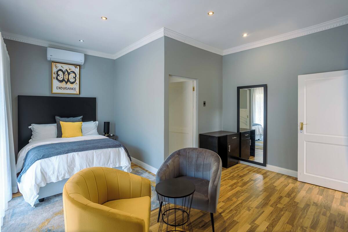 Ein Schlafzimmer mit Bett, Stuhl, Schminktisch und Spiegel.