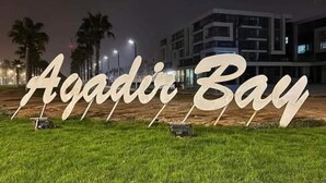 Un panneau indiquant la baie d’Agadir, avec un bâtiment moderne en arrière-plan.