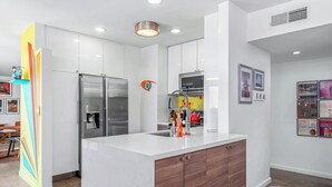 Een moderne keuken met witte kasten, een roestvrijstalen koelkast en een houten aanrecht.