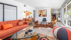 Een moderne woonkamer met een bank, stoelen, een glazen salontafel en een vloerkleed.