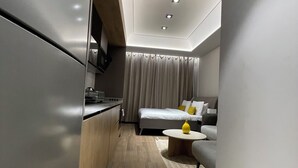 Ein modernes, kompakter Wohnraum mit Küchenzeile, einem Bett und einer Sitzecke.