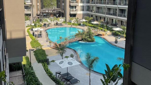 Ein modernes Apartmenthaus mit Schwimmbad und Sitzbereichen im Freien.