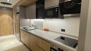 Eine moderne Küche mit Holzschränken, einem Edelstahlkühlschrank, einer Mikrowelle und einem Backofen.