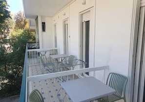 Ein Balkon mit Tisch, Stühlen, einem Metallgeländer und einer Tür.