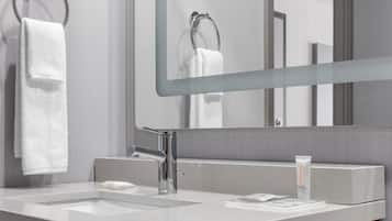 Un baño moderno con un espejo grande, dos lavamanos y un perchero para toallas.