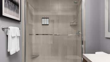 A modern bathroom with a glass-enclosed shower, a white sink, and a towel rack.