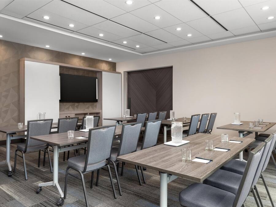 A conference room with a long table, chairs, a whiteboard, and a large screen.