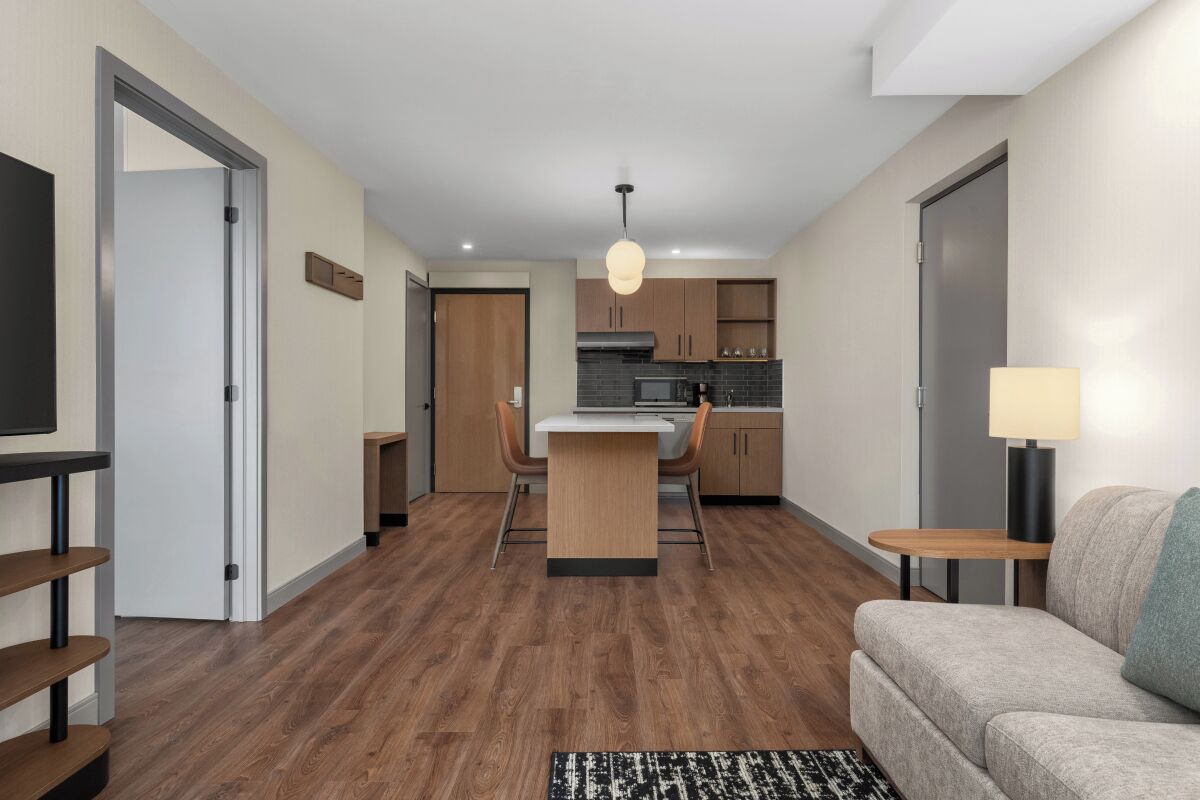 Un apartamento moderno con comedor, kitchenette y sala de estar con sofá y lámpara.