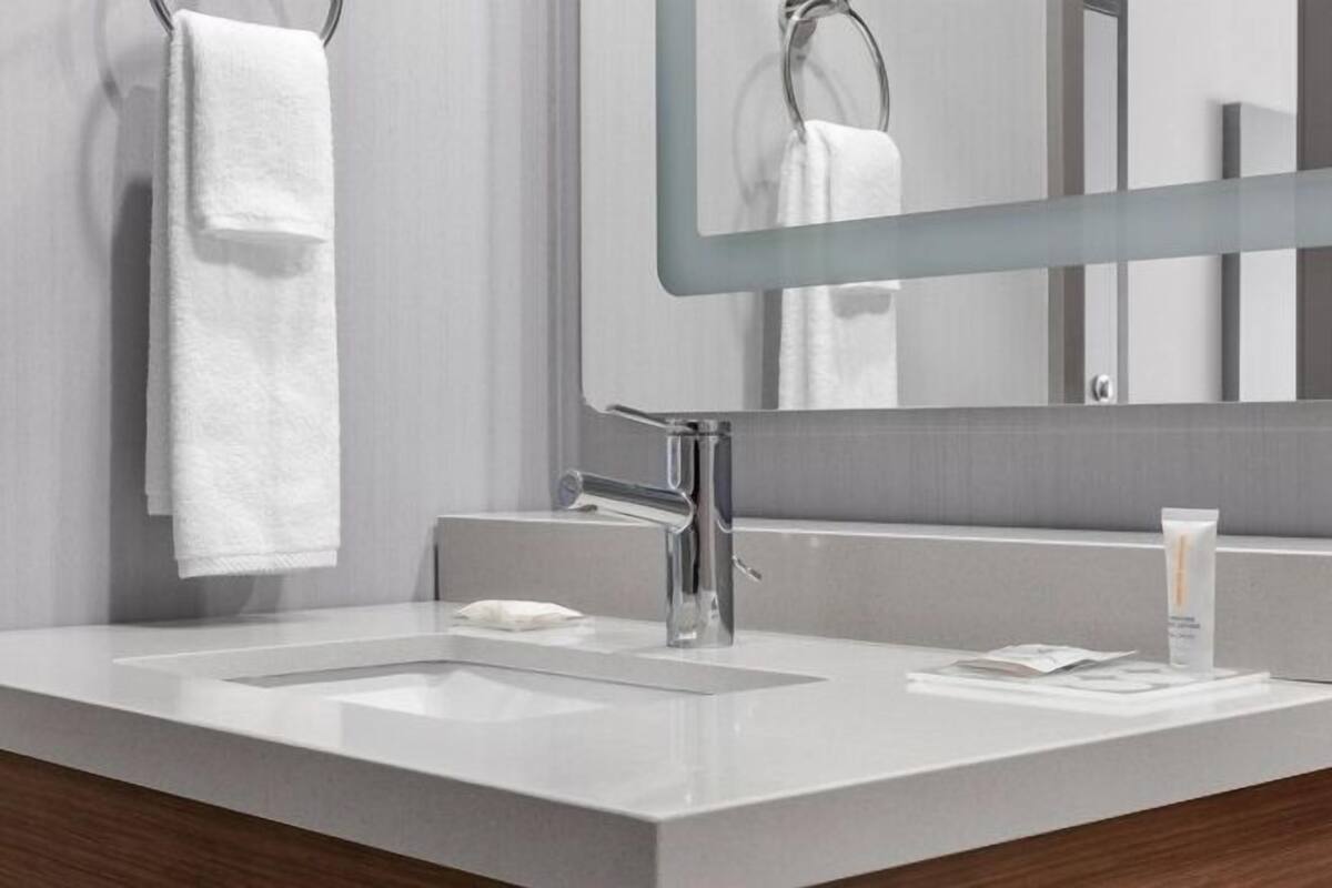A modern bathroom with a large mirror, two sinks, and a towel rack.