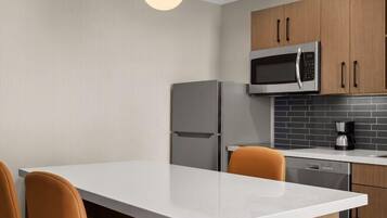 Een moderne keuken met een wit aanrecht, roestvrijstalen apparatuur en houten kastjes.