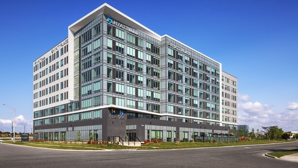 A modern hotel building with a glass facade, multiple floors, and a prominent sign reading "HYATT HOUSE".