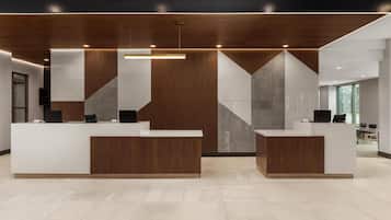 Un espace d’accueil doté de deux comptoirs de réception blancs, d’éléments décoratifs en bois et d’un motif géométrique sur le mur.