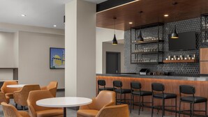 A modern bar area with round tables and bar stools, a patterned wall, and a mounted TV.