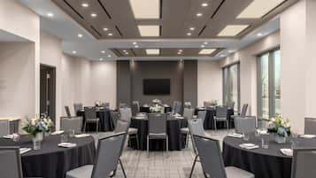 A conference room with round tables, grey chairs, and black tablecloths.