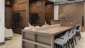 A modern conference room with a long table, white chairs, wooden panel walls, and a flat-screen TV.