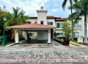 A covered entrance with a tiled roof, palm trees, and a building with a white facade and red-tiled roof. - Gorgeous Villa Marina Vallarta, pool, Free Shuttle (Puerto Vallarta)