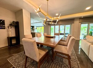 A modern dining area with a large wooden table, six upholstered chairs, and a geometric pendant light. - Gorgeous Villa Marina Vallarta, pool, Free Shuttle (Puerto Vallarta)