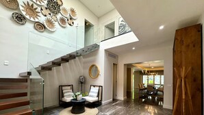 A spacious living area with a high ceiling, a glass staircase, a dining area, and a view of the outdoors. - Gorgeous Villa Marina Vallarta, pool, Free Shuttle (Puerto Vallarta)