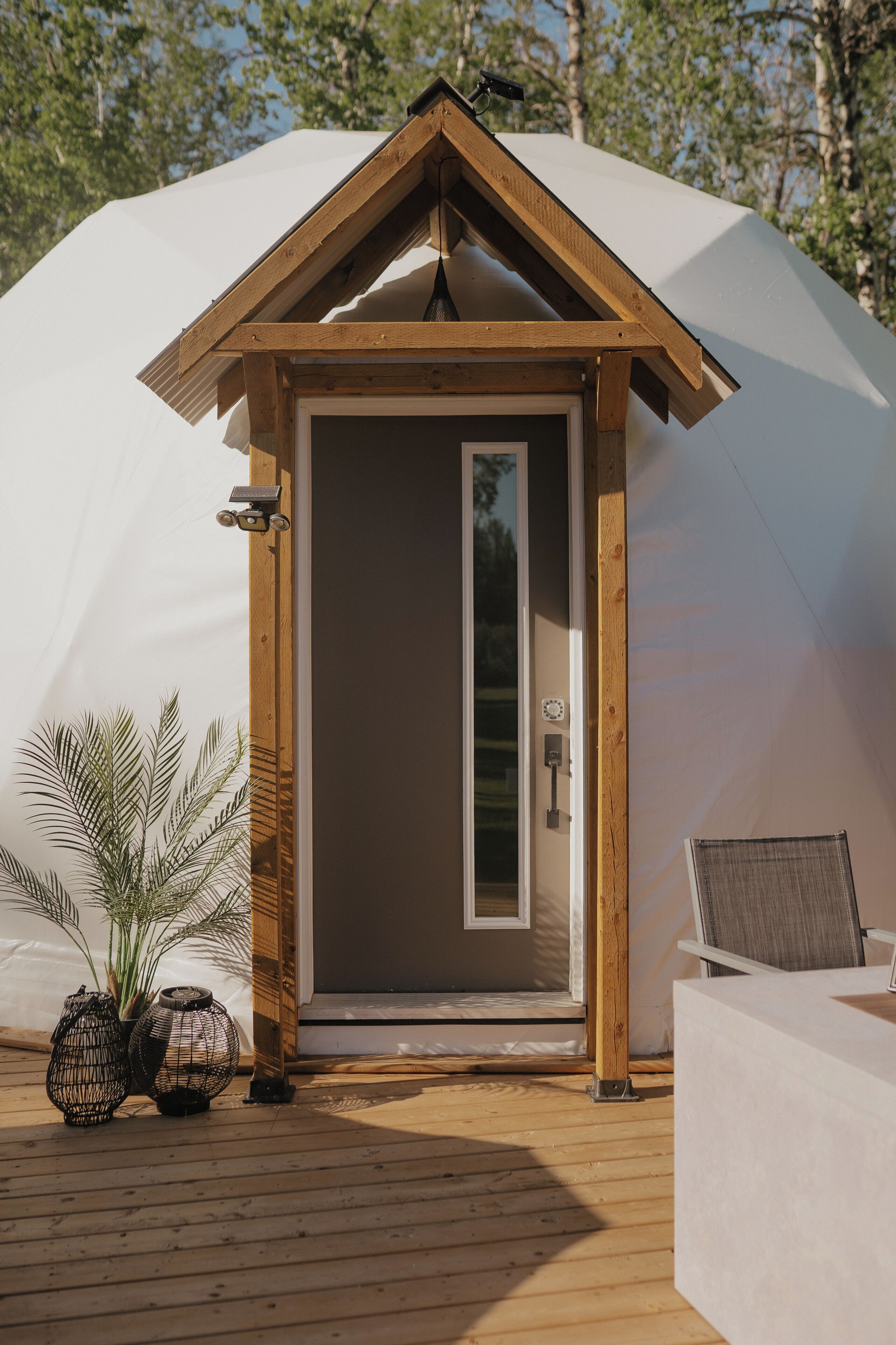 A wooden door with a small porch leading to a white tent-like structure.