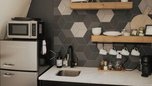 Een keuken met een magnetron, spoelbak en houten planken.