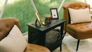 Een gezellige kamer met twee bruine leren fauteuils, een klein zwart tafeltje met een kaars en een ingelijst certificaat, en een zacht wit vloerkleed op een houten vloer.