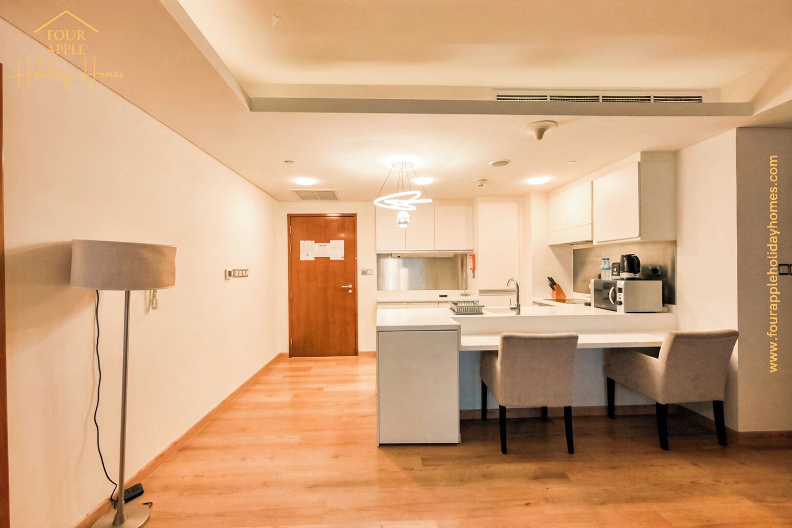 A modern kitchen with a central island, a dining area with chairs, and a hallway leading to a door.