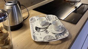 Eine moderne Küche mit eingebautem Herd, einem Wasserkocher und einer Ablage mit Tassen und einem Korb.