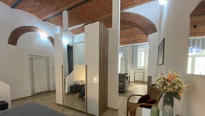 Ein Schlafzimmer mit einem Bett, einem Schminktisch, einem Spiegel, einem Sessel und einem Tisch mit Blumen.