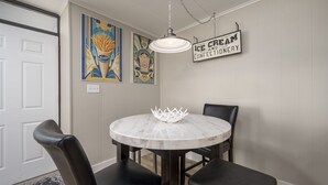 Een eetgedeelte met een ronde marmeren tafel, zwarte lederen stoelen en een witte kroon als decoratie.